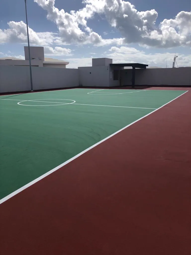 Cancha deportiva terminada con PASA Sport en verde y rojo, con líneas blancas