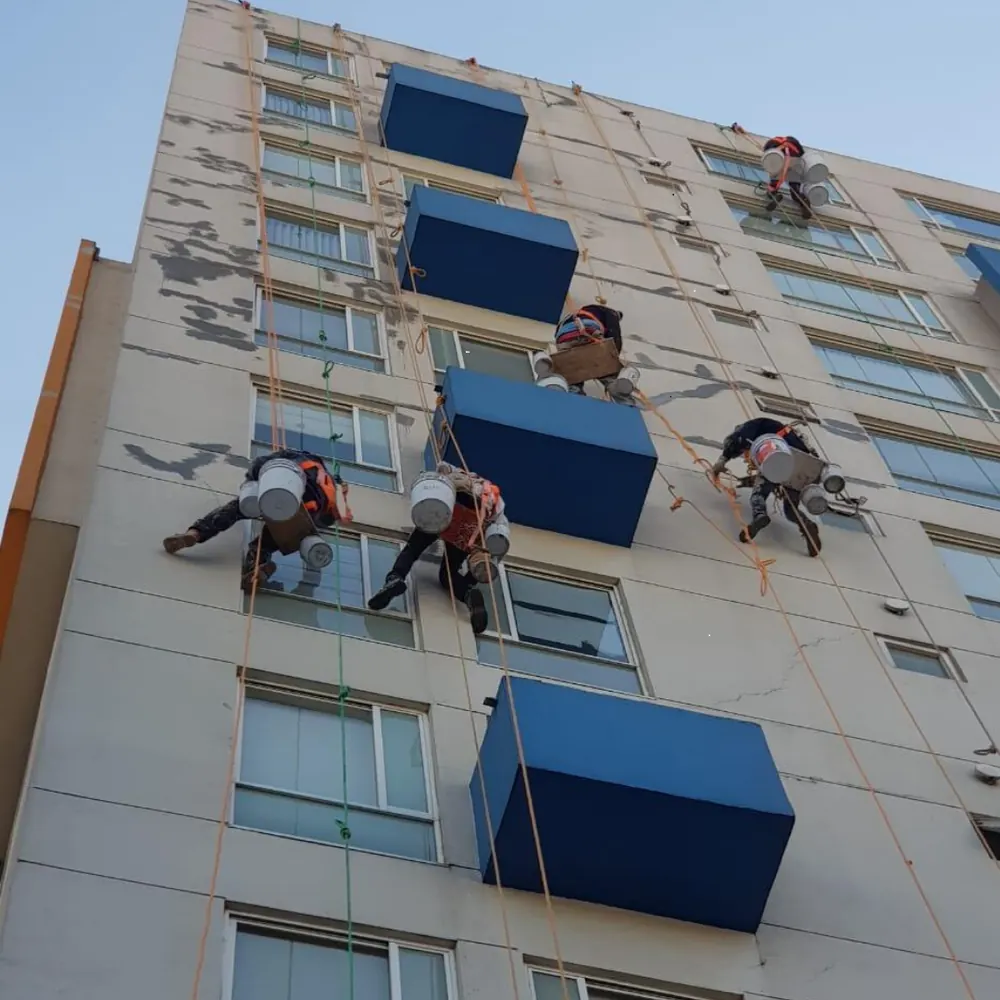 Cuadrilla en rapel pintando la fachada de un edificio